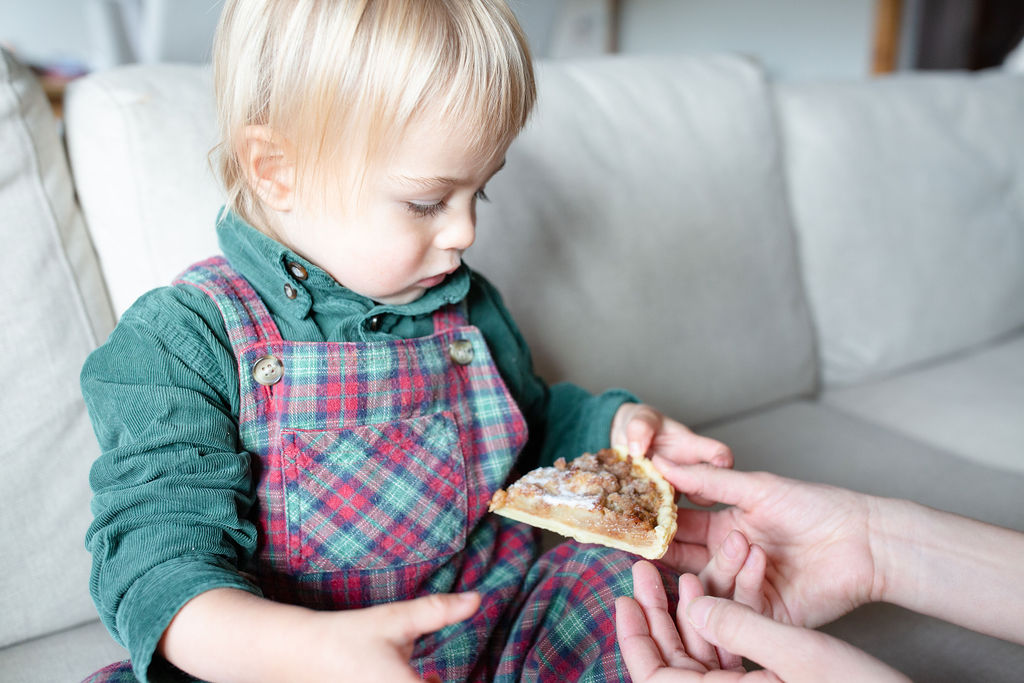 hands giving a pie slice to a toddler