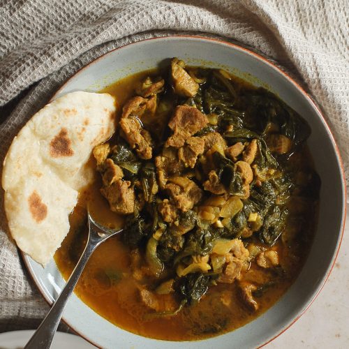 Lamb and spinach curry with a piece of naan bread