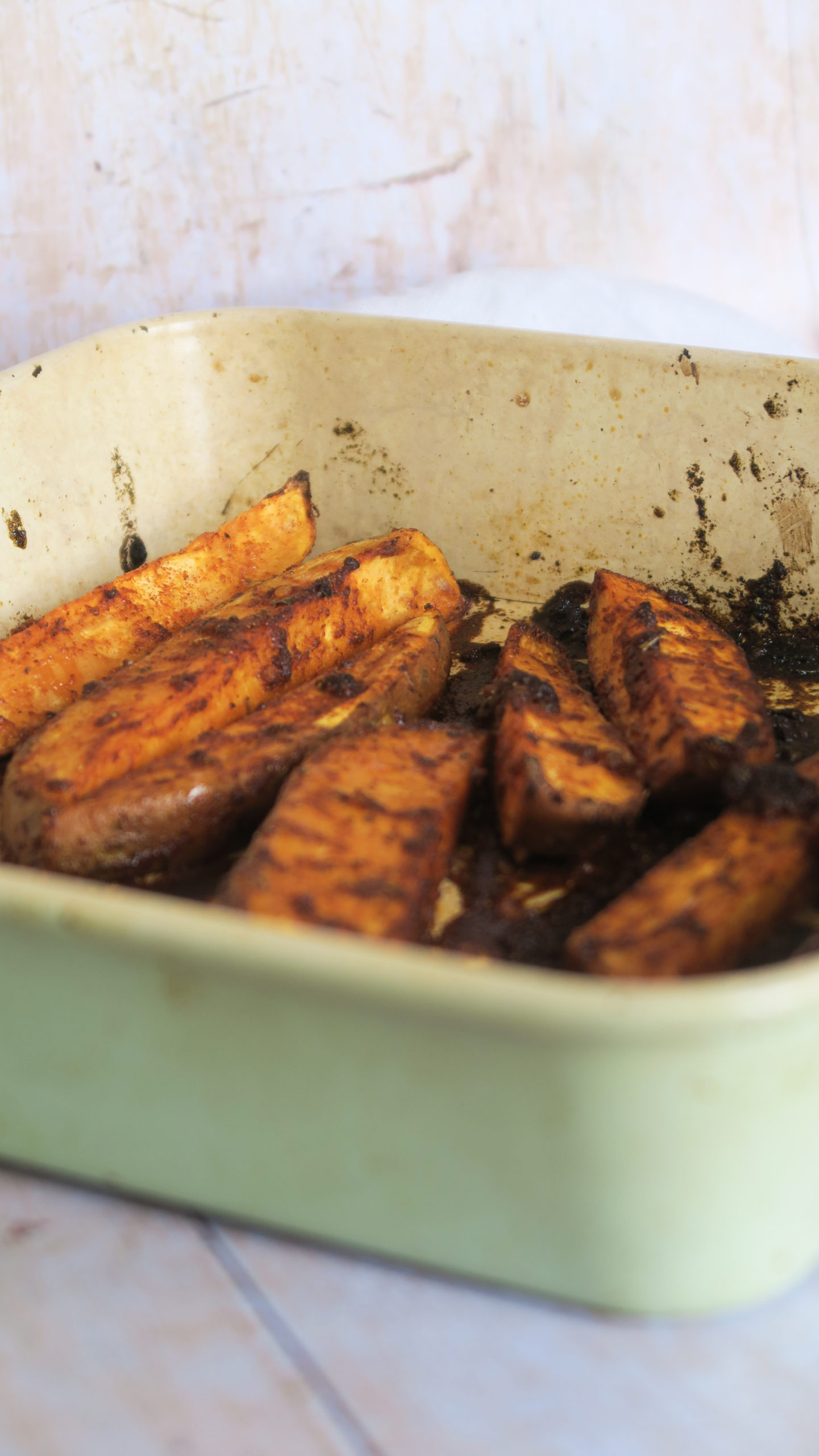 Peri peri sweet potato wedges in a green baking tray 