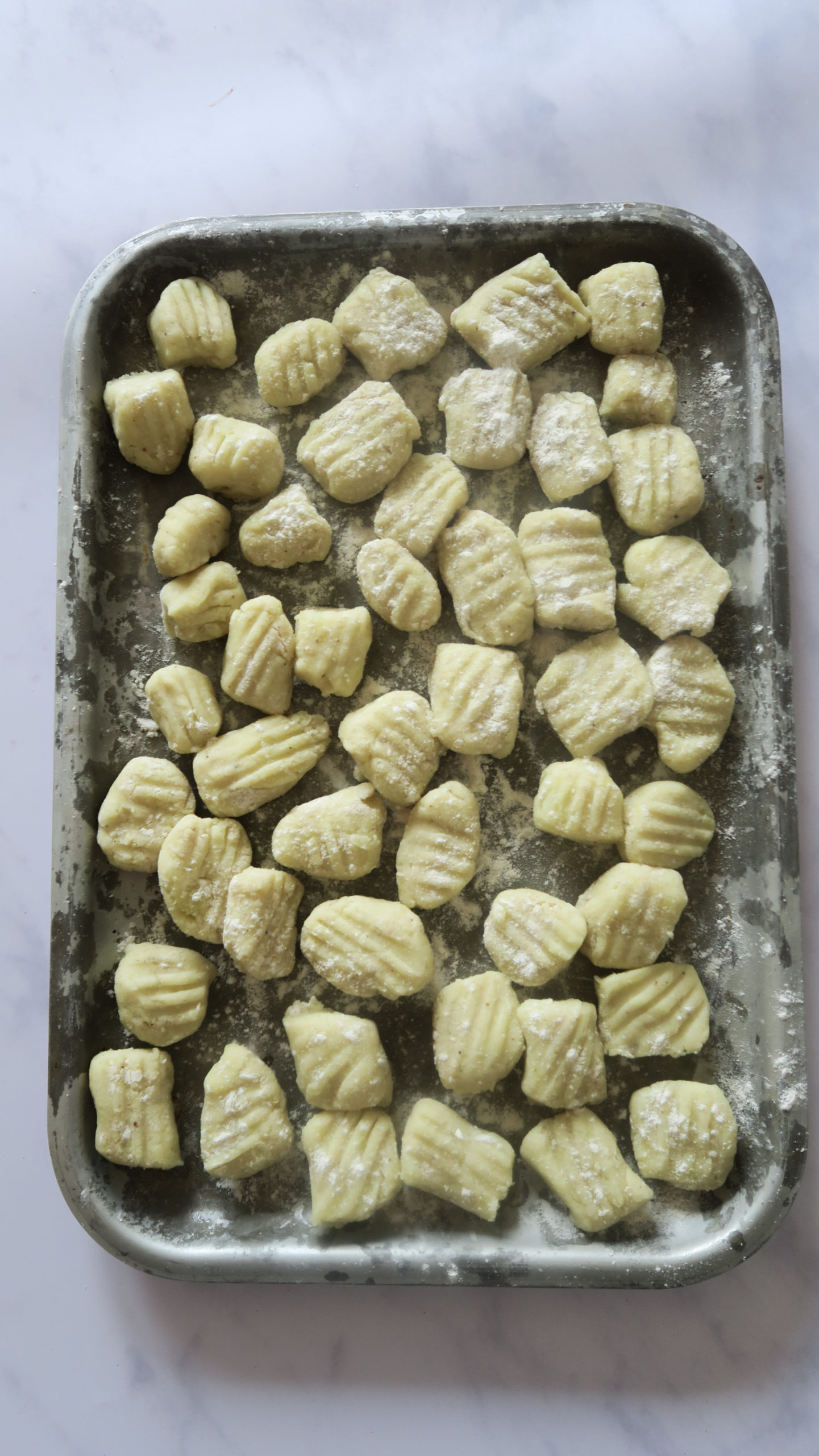 vertical image of pre-cooked gnocchi on a tray