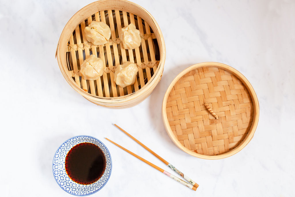 Momo dumplings in a bamboo steamer and bowl of soy sauce and chopsticks
