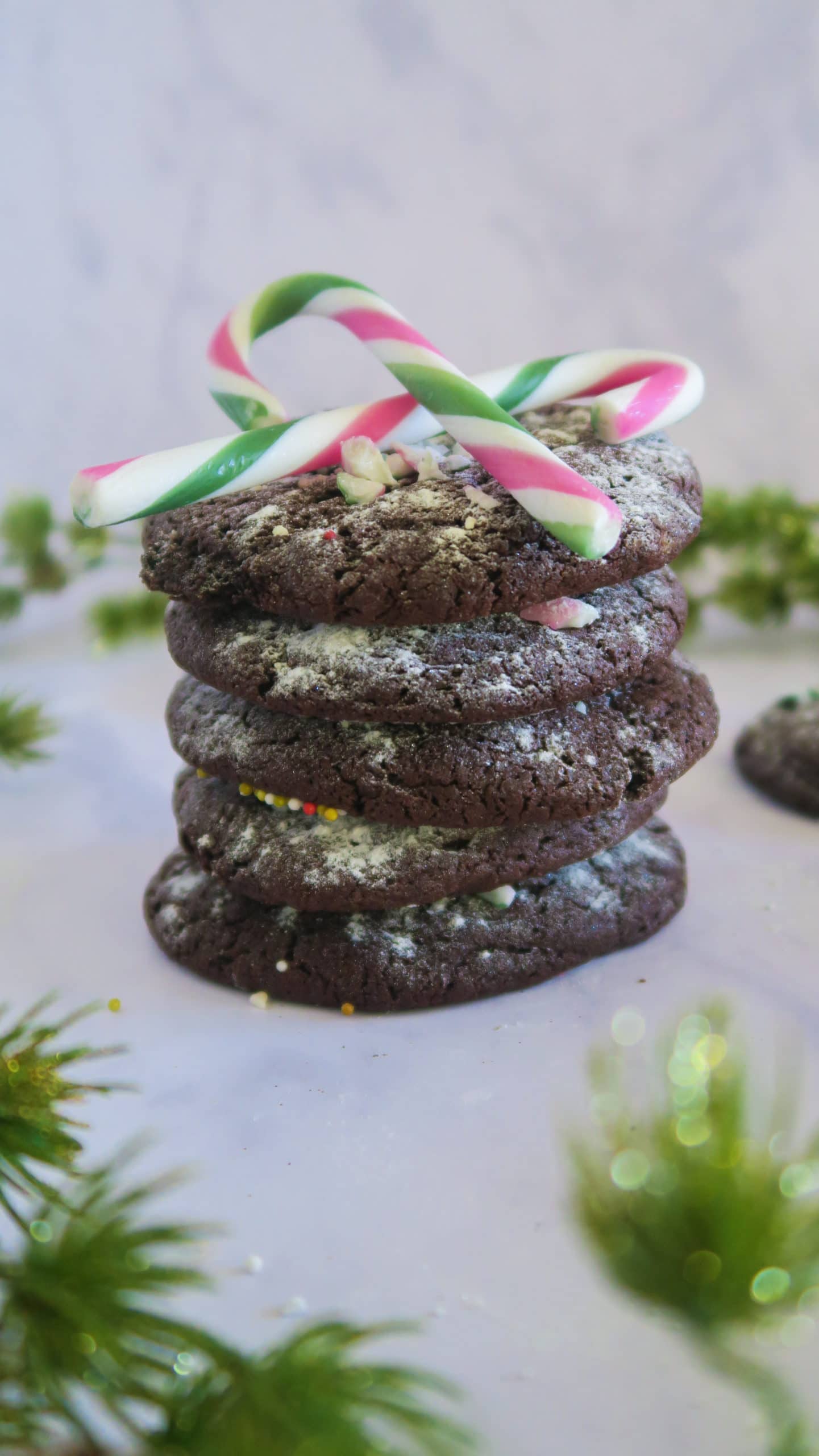 A stack of chocolate peppermint cookies with candy canes balanced on top