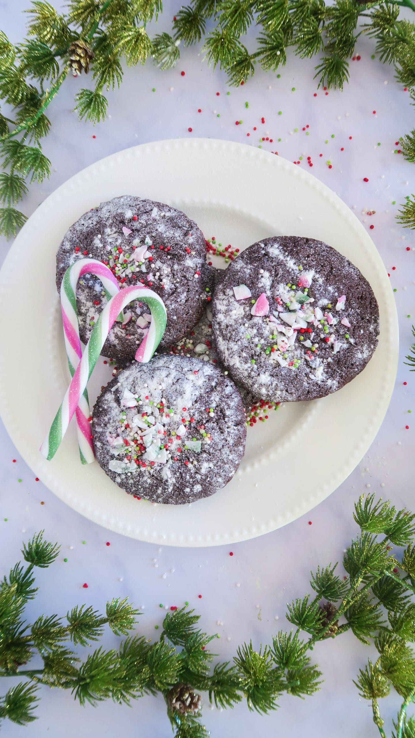 chocolate peppermint cookies on a plate with candy canes on the side