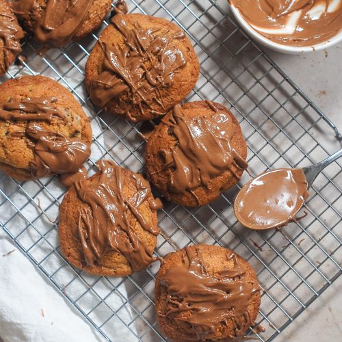 Crunchy peanut butter cookies on a cooling rack, drizzled with Nutella