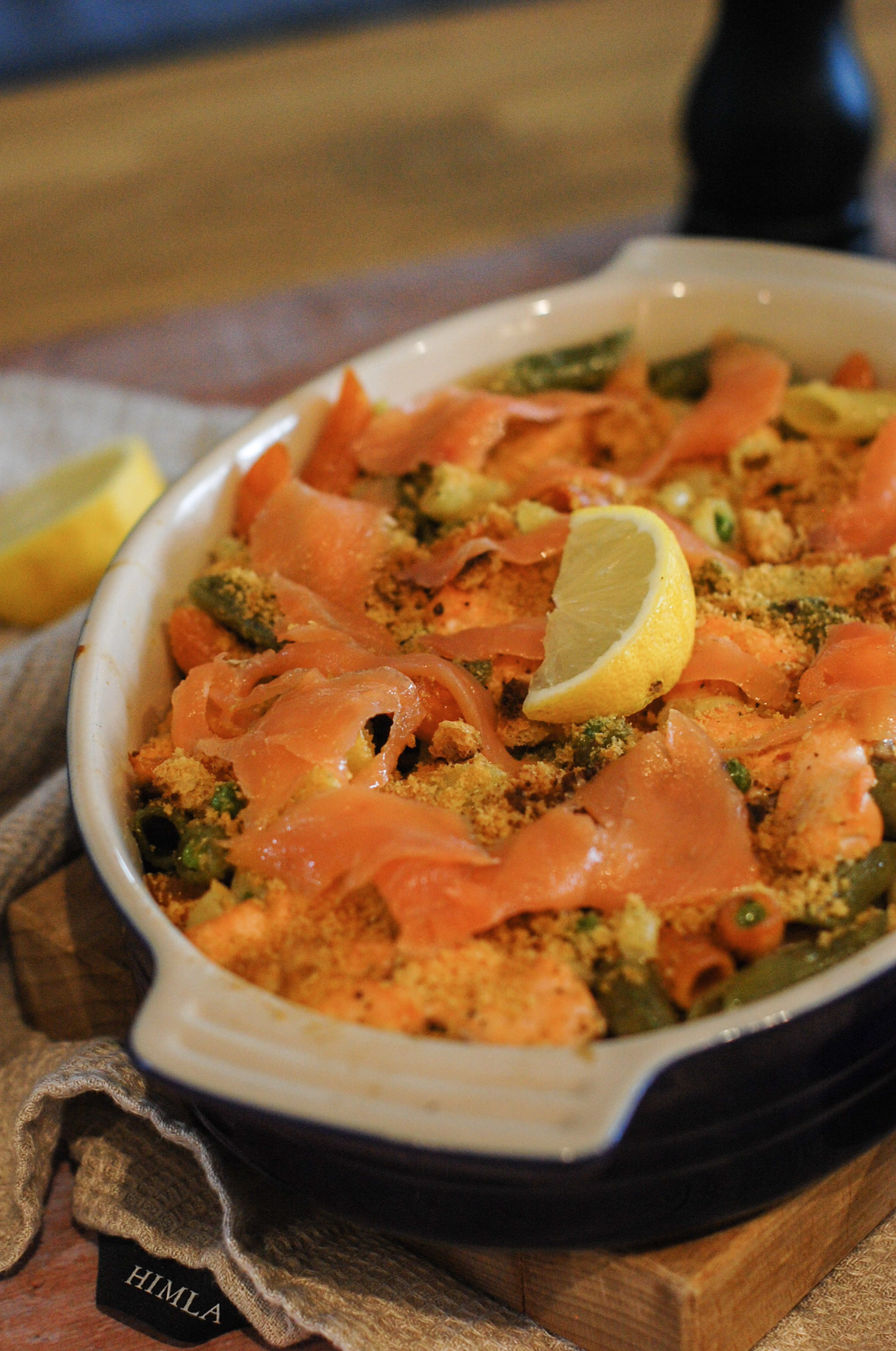 salmon pasta bake topped with smoked salmon and a lemon wedge