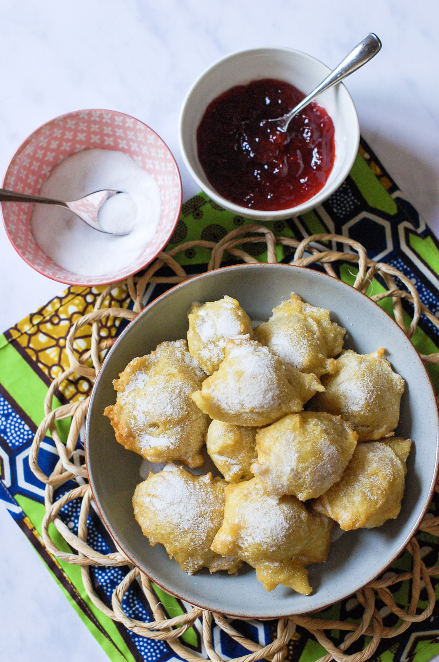 a bowl of mini doughnuts with jam and sugar