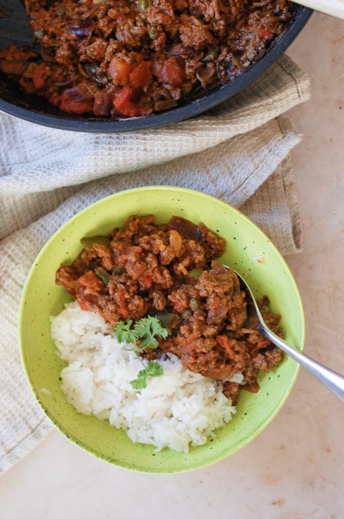 a green bowl full of beef picadillo and rice.