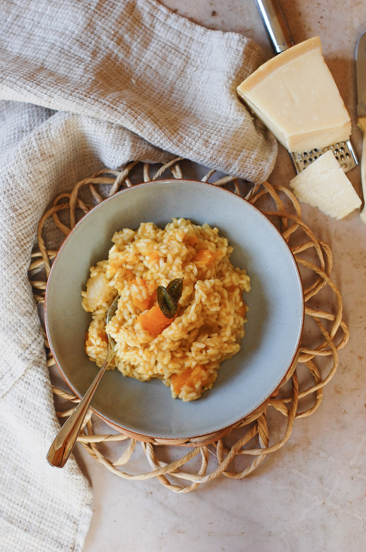 a bowl of risotto on a placemat with a parmesan wedge