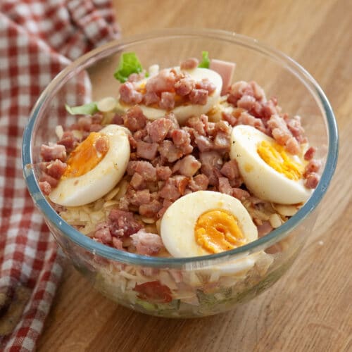 A small bowl of salad with eggs and bacon bits