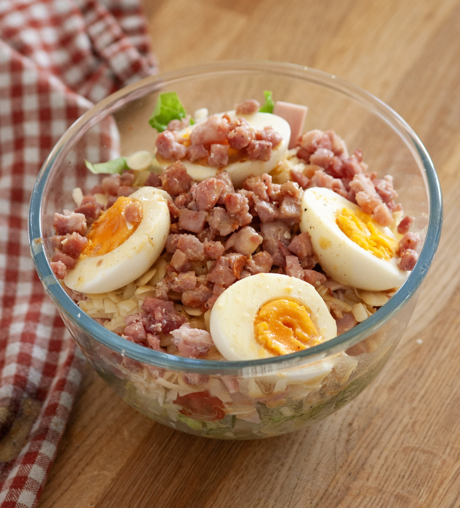 A small bowl of salad with eggs and bacon bits
