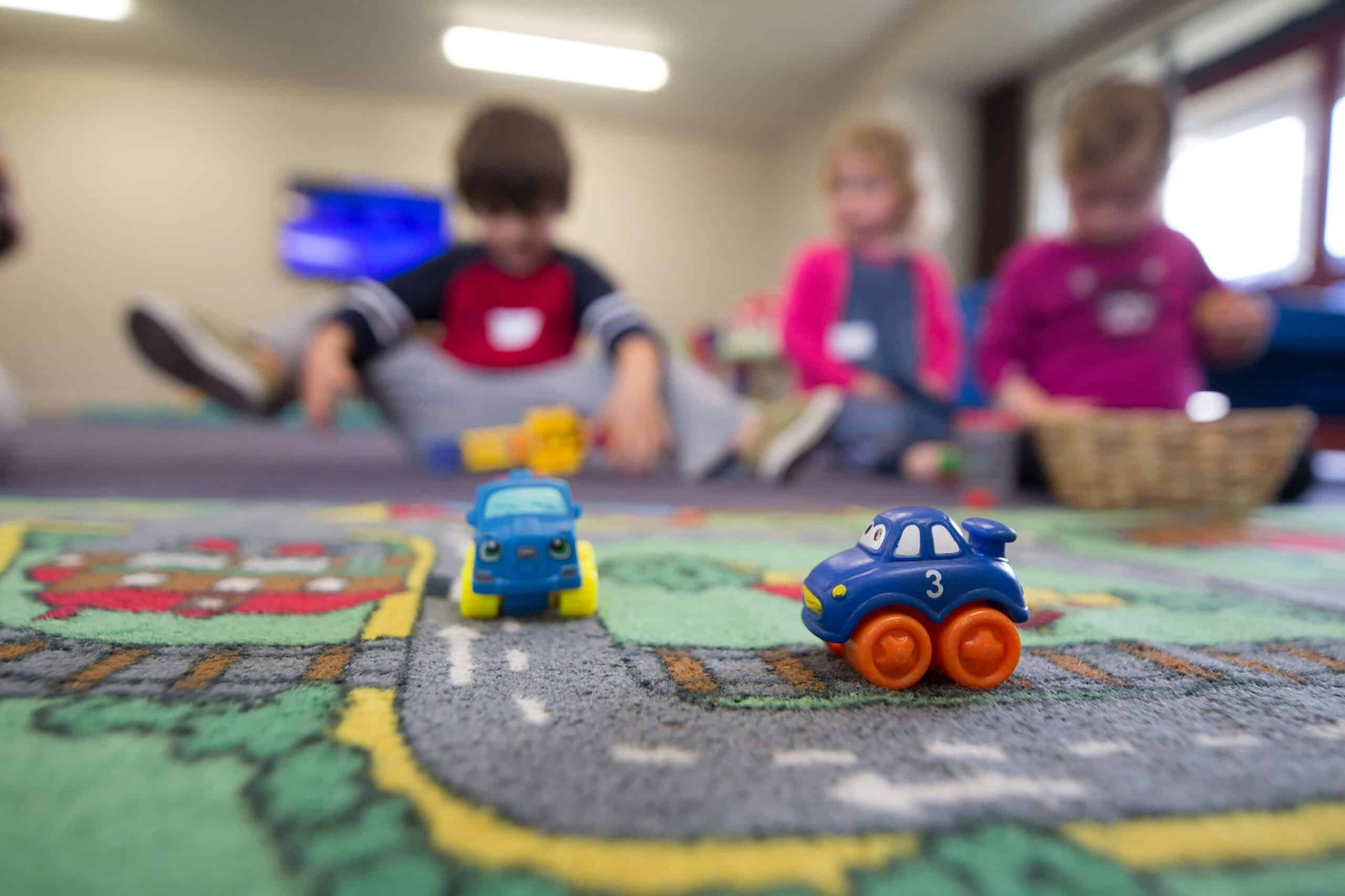 kids playing with toy cars on a toy road mat